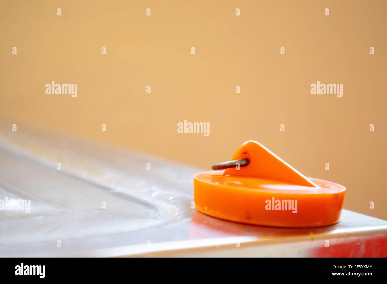 Kapstadt, Südafrika - 06-04-2021 Kreative Ansicht des leuchtend orangefarbenen Spültischstopfens, der auf der Oberfläche des Spülbeckens in der Küche ruht. Haus- und Reinigungskonzept. Stockfoto