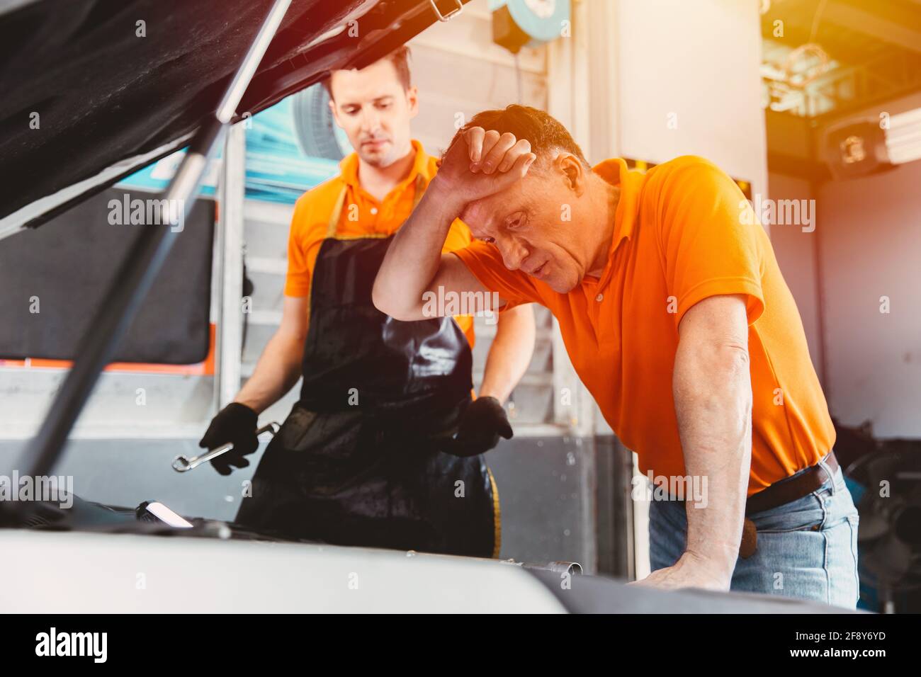 Autotechniker Ingenieur Service-Team gestresst krank müde Mann mit Probleme mit einem defekten Motor des Kunden, der die Fahrzeughaube in betrachtet auto-Garage Stockfoto