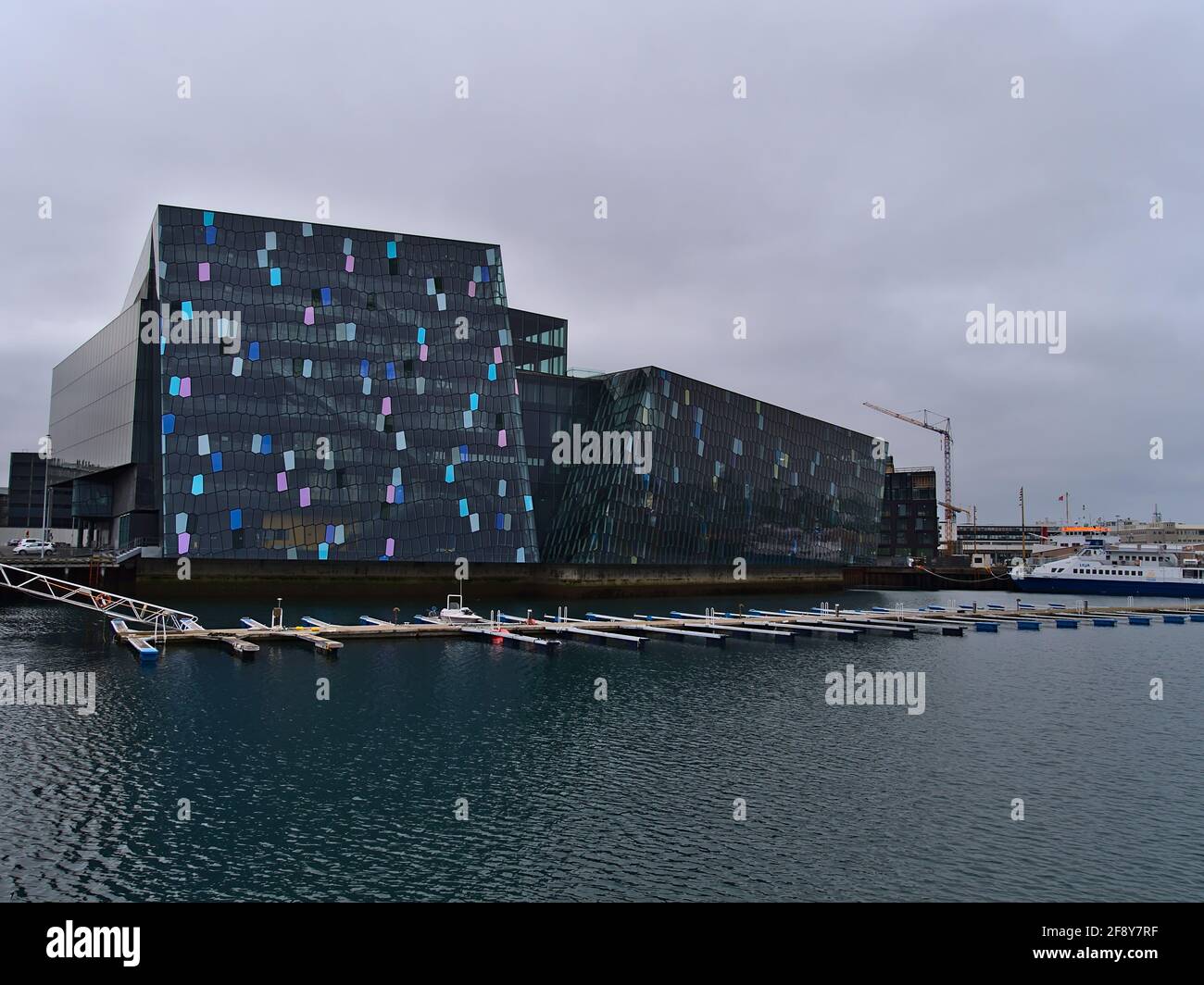 Blick auf die berühmte Konzerthalle und das Konferenzzentrum Harpa in der Innenstadt von Reykjavik mit einer farbenfrohen, strukturierten Glasfassade, die von Basaltformationen inspiriert ist. Stockfoto