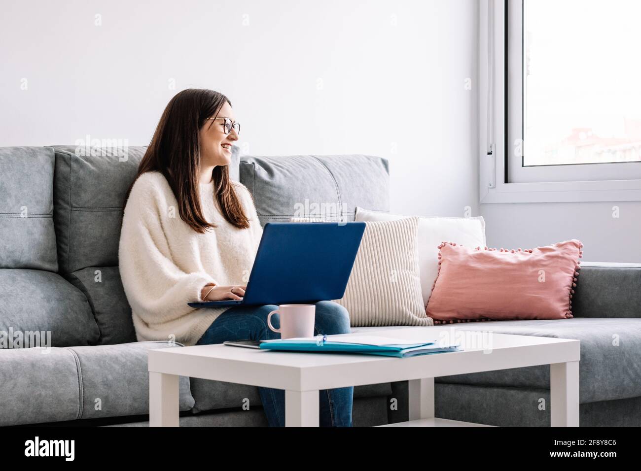 Frau mit Laptop auf ihrem Sofa zu Hause Stockfoto