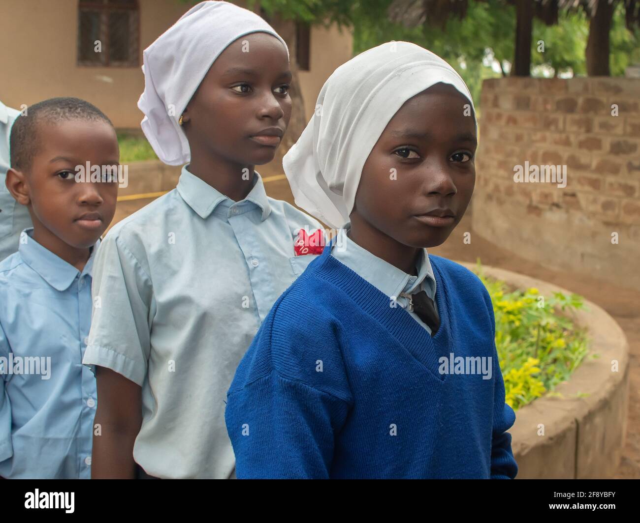 Dodoma, Tansania. 08-18-2019. Porträt von drei muslimischen schwarzen Mädchen, die Schlange stehen, um ihr Mittagessen zu bekommen, nachdem die Schule in einem abgelegenen Dorf beendet ist Stockfoto