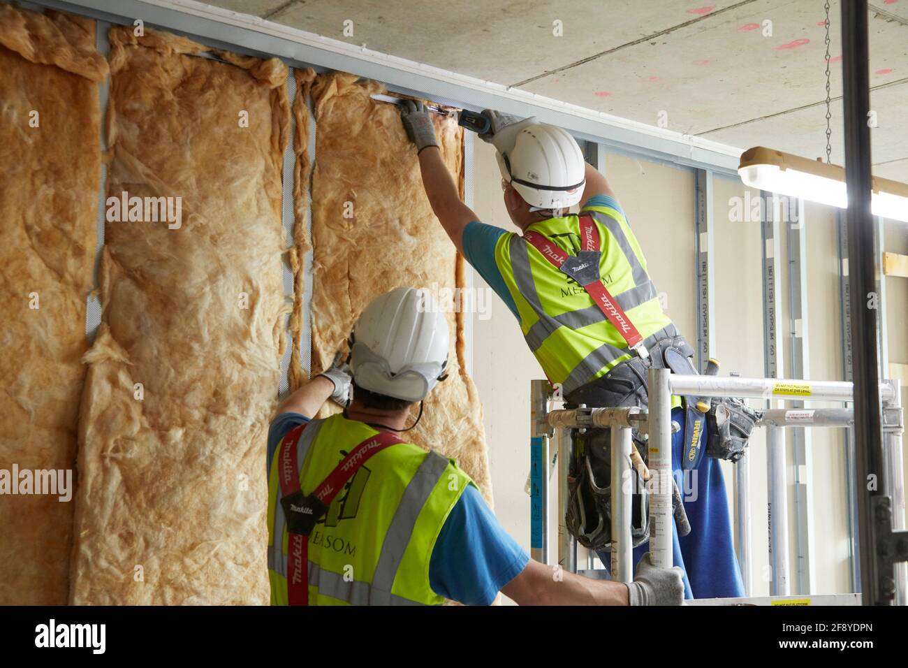 Die Bauarbeiter auf der Baustelle montieren die Isolierung an die Stollenwand Stockfoto