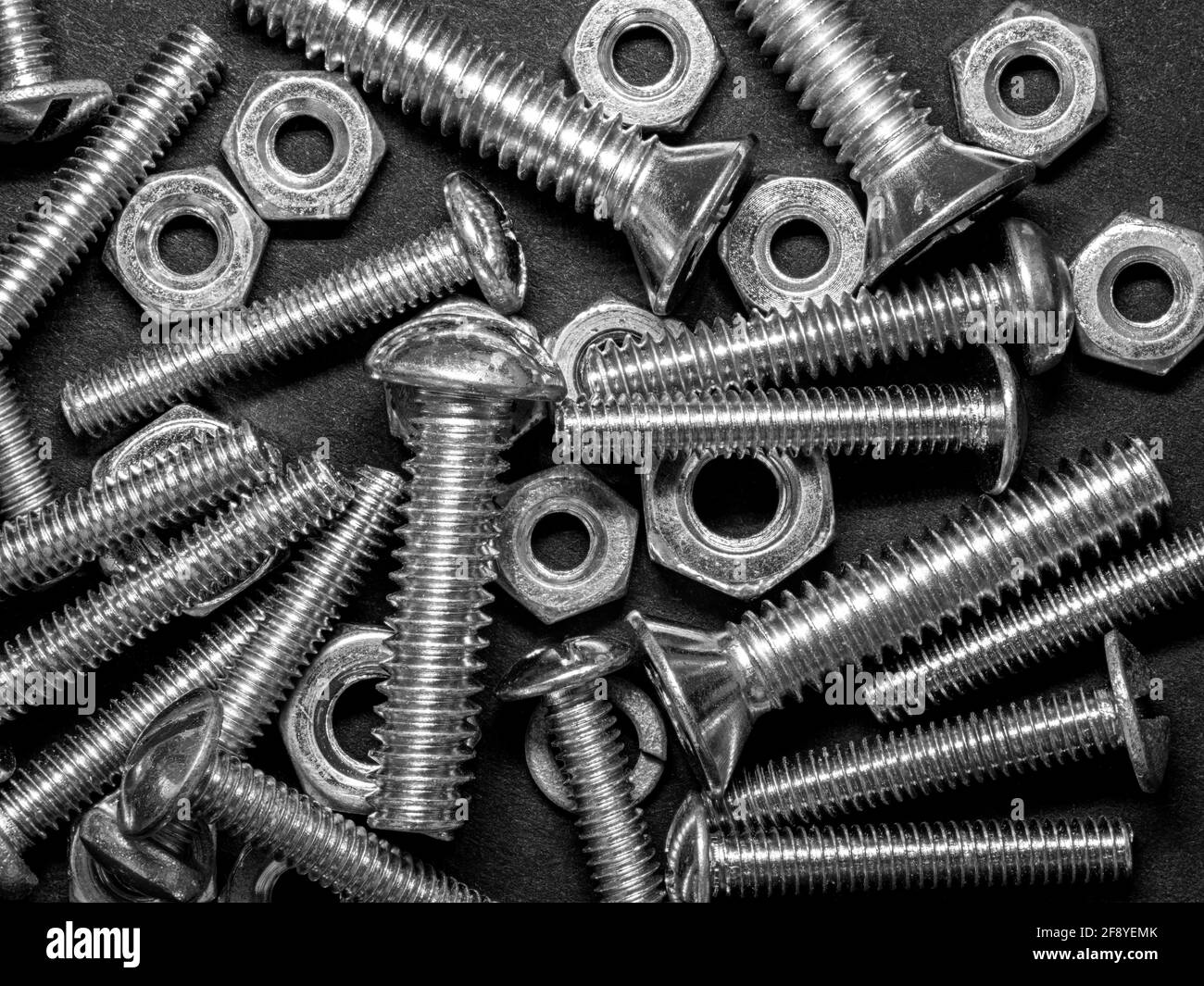 Schwarzweiß-Foto mit Nahaufnahme von Metallmuttern und Schrauben Stockfoto