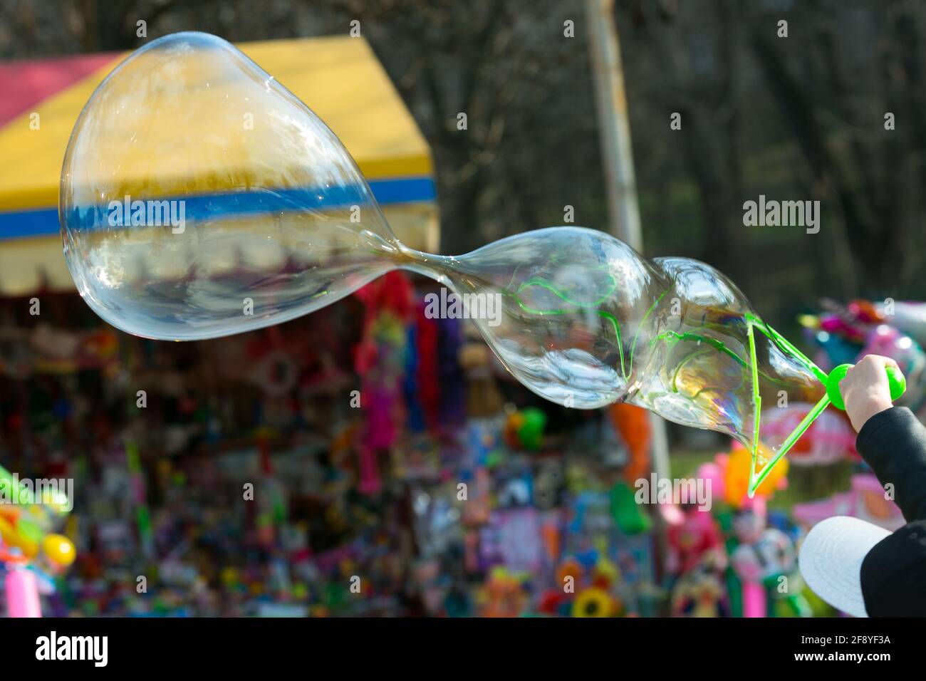 Helle große Seifenbälle im Park. Kinder blasen Seifenblasen auf und schöne Schaumbälle hängen in der Luft. Stockfoto