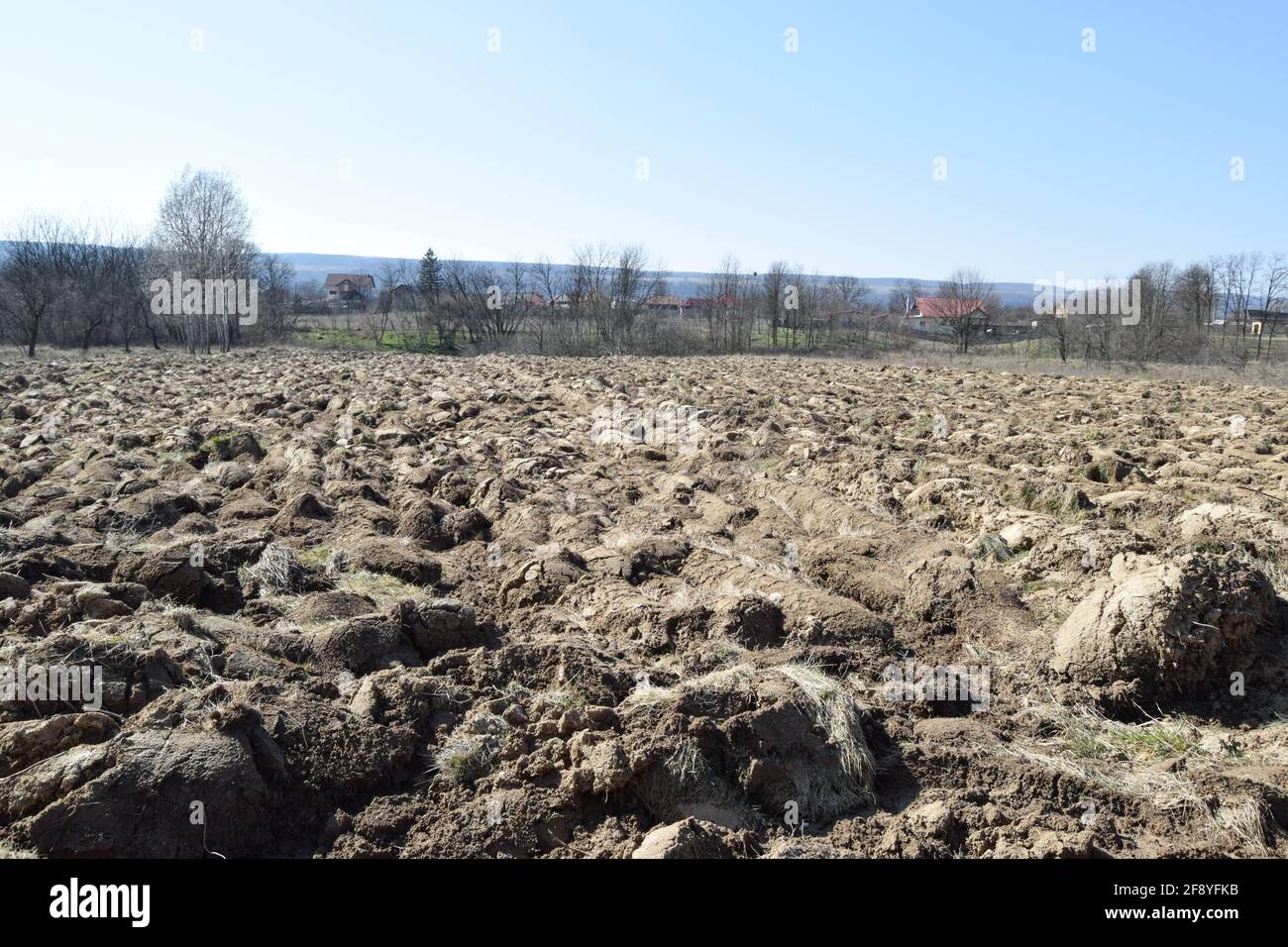 Landwirtschaftlicher Hintergrund von gepflügten Furchen bereit für neue Kulturen. Der Prozess der Vorbereitung des Bodens vor der Pflanzung. Nahaufnahme von trockener Erde im Feld mit Stockfoto