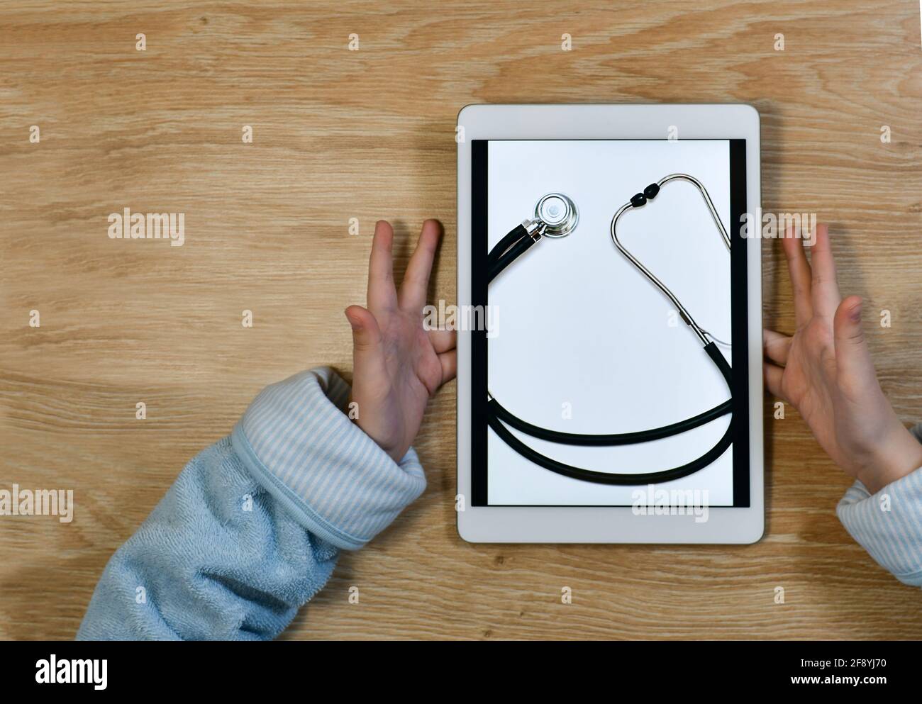 Lächeln Sie auf dem Tablet-Bildschirm, gezeichnet von einem Stethoskop. Und öffnen Sie mit Freude und überraschen Palmen. Medizinische Online-Pflege. Stockfoto