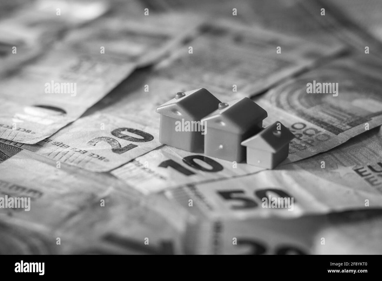 Tisch mit Euro-Banknoten bedeckt mit Häusern auf der Oberseite. Immobilieninvestitionskonzept Stockfoto