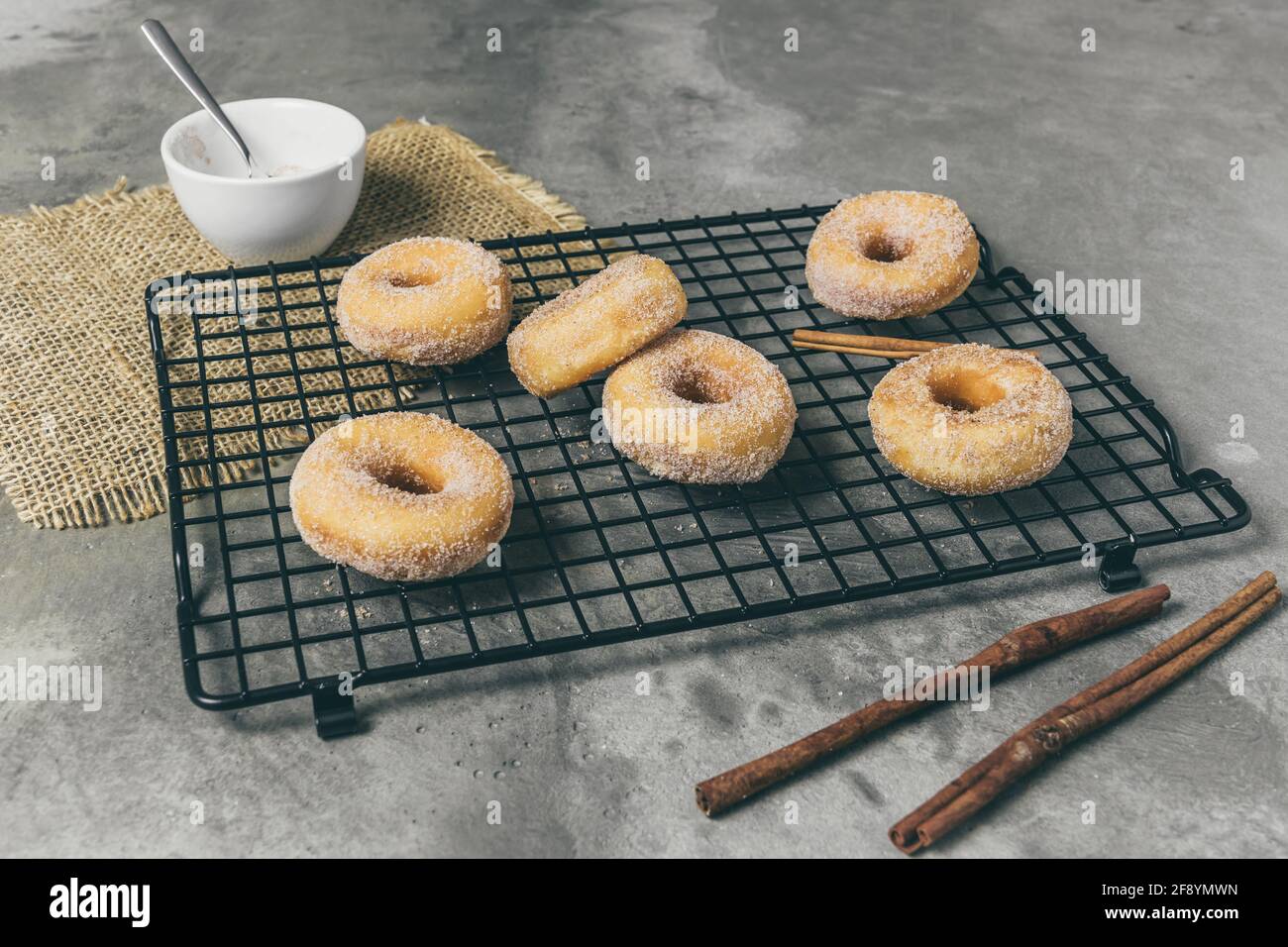 Gezuckerte Mini-Donuts mit Zimt auf einem Kühlgestell Ein grauer Hintergrund Stockfoto