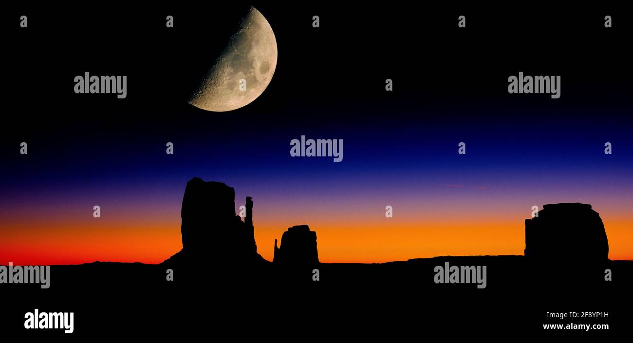 Mond bei Sonnenaufgang über Silhouetten von Mitten Buttes und Merrick Butte, Monument Valley, Arizona, USA Stockfoto