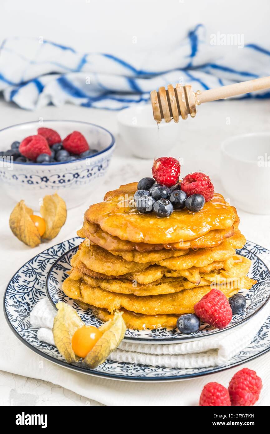 Haufen veganer Pfannkuchen mit Beeren und Sirup auf weißem Hintergrund, vertikal Stockfoto