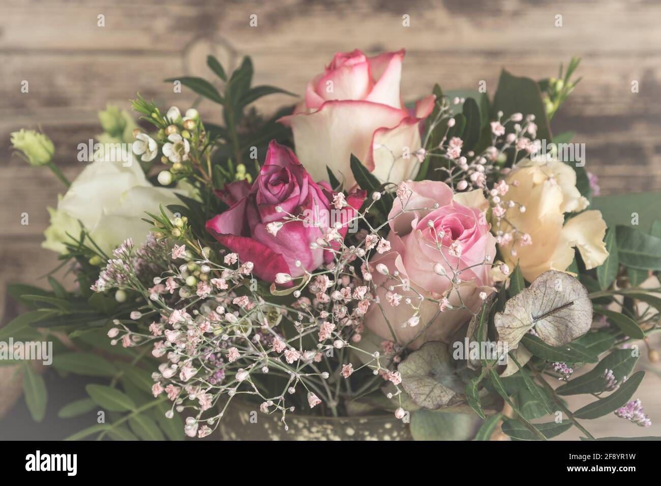 Blumenstrauß mit rosa und weißen Rosen auf Holzhintergrund, Vintage-Stil Stockfoto