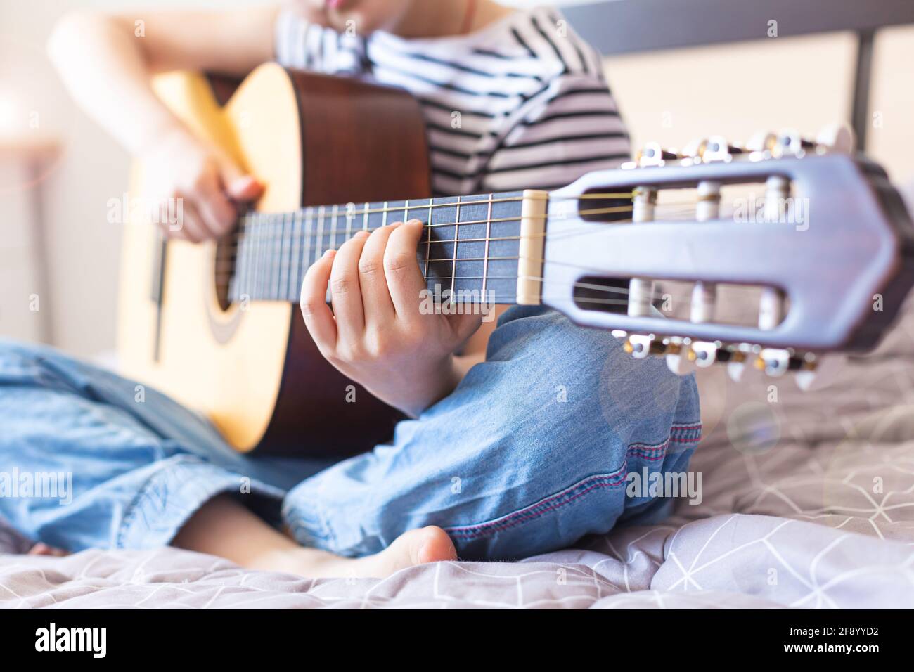 Das Kind spielt eine akustische Gitarre. Online lernen, ein Musikinstrument zu spielen Stockfoto