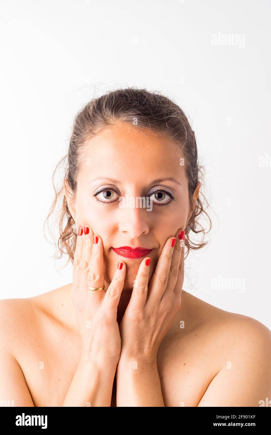 Porträt einer kaukasischen Frau mit roten Lippen und Nägeln, Haare und Hände auf ihrem Gesicht gesammelt, auf weißem Hintergrund. Stockfoto