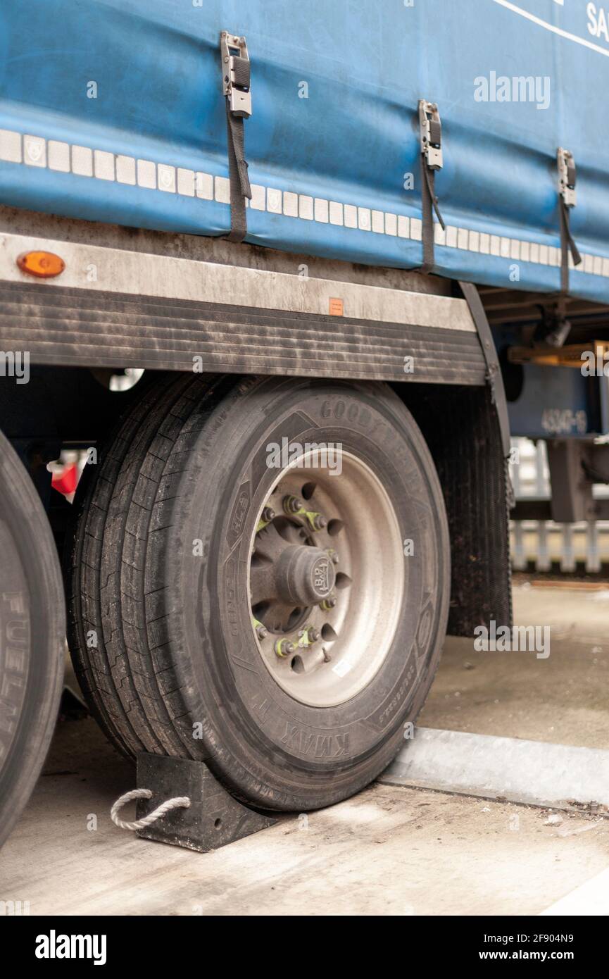 Sattelschlepper mit schwarzem Gummirad-Unterlegkeil, der die sichert Anhänger als zusätzlicher Sicherheitsschritt vertikal Stockfoto