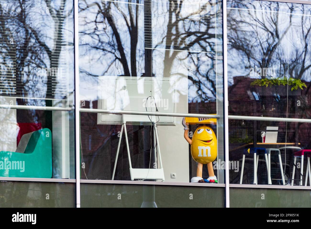 Die große, gelbe Zahl von M's allein im leeren Bürogebäude während der Corona-Virus-Pandemie. Dies ist das Maskottchen der Schokoladenmarke m&m's pro Stockfoto