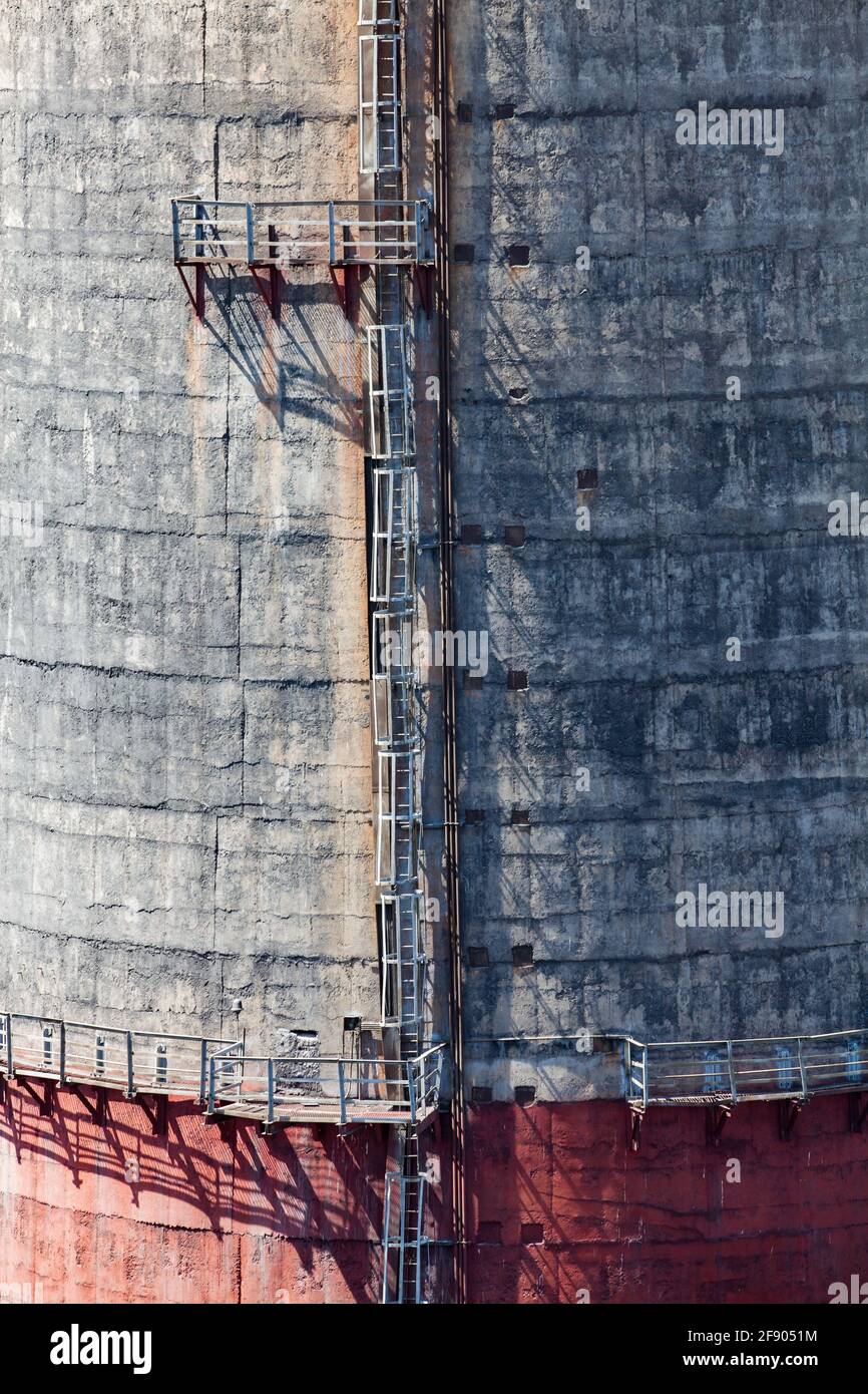 Ekibastuz, Kasachstan. WÄRMEKRAFTWERK GRES-1. Nahaufnahme des Beton-Rauchstapels. Roter Boden, Metalltreppe. Struktur und Schatten der Betonoberfläche. Stockfoto