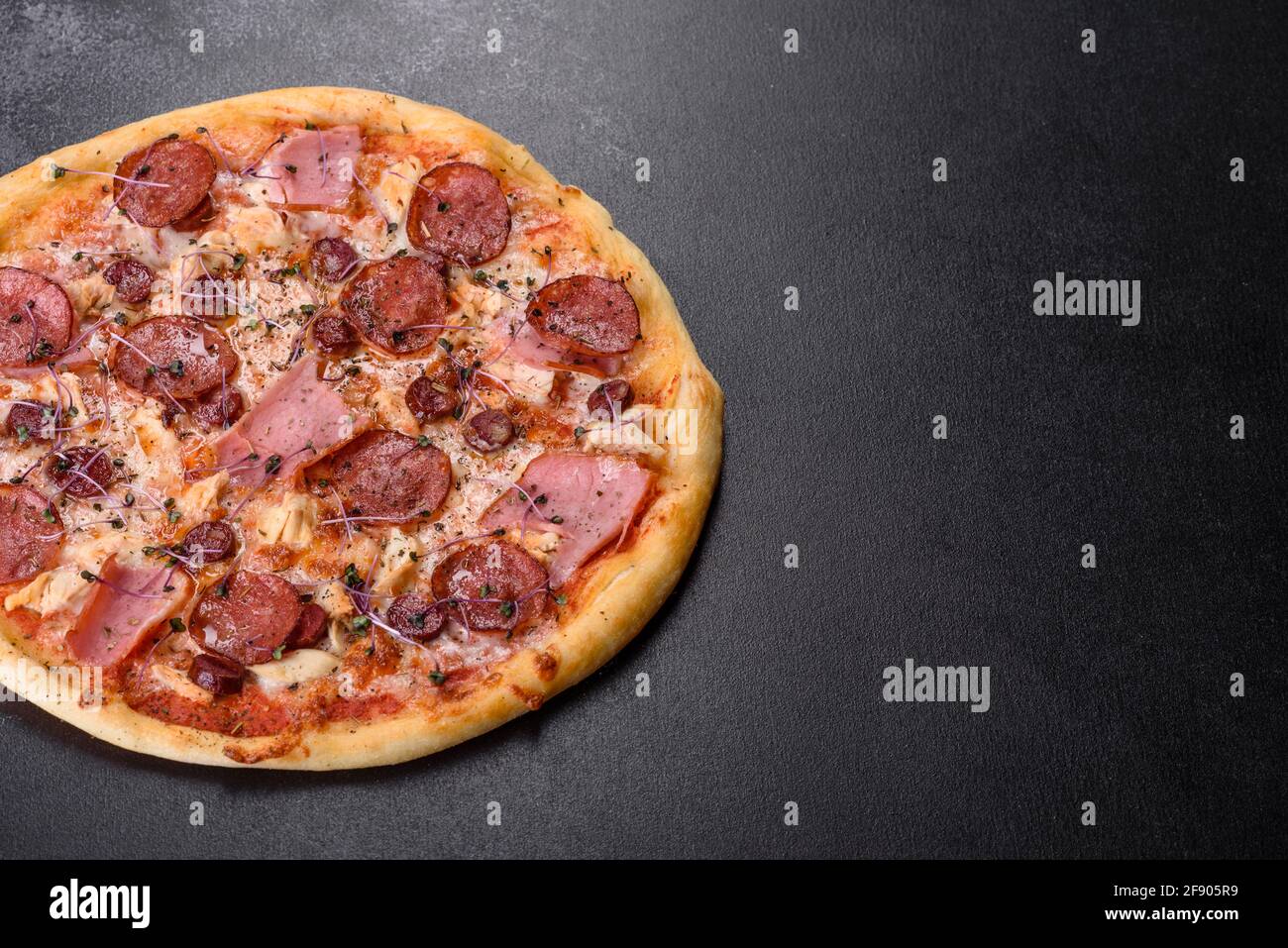 Köstliche frische Ofenpizza mit Tomaten, Salami und Speck auf dunklem  Betonboden. Italienische Küche Stockfotografie - Alamy