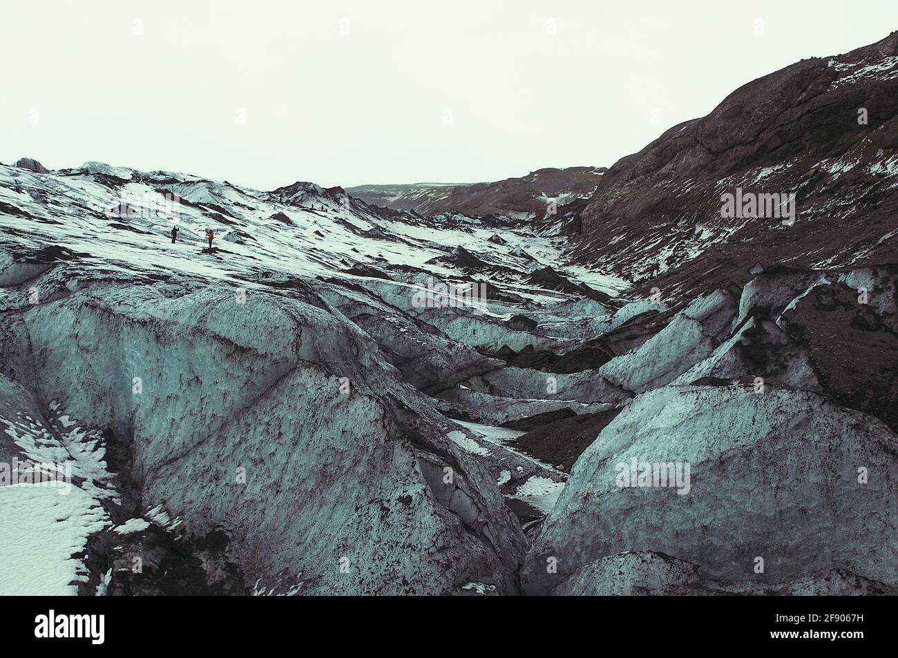 Fernansicht von zwei Menschen, die im Winter auf felsiger Landschaft stehen, Island Stockfoto