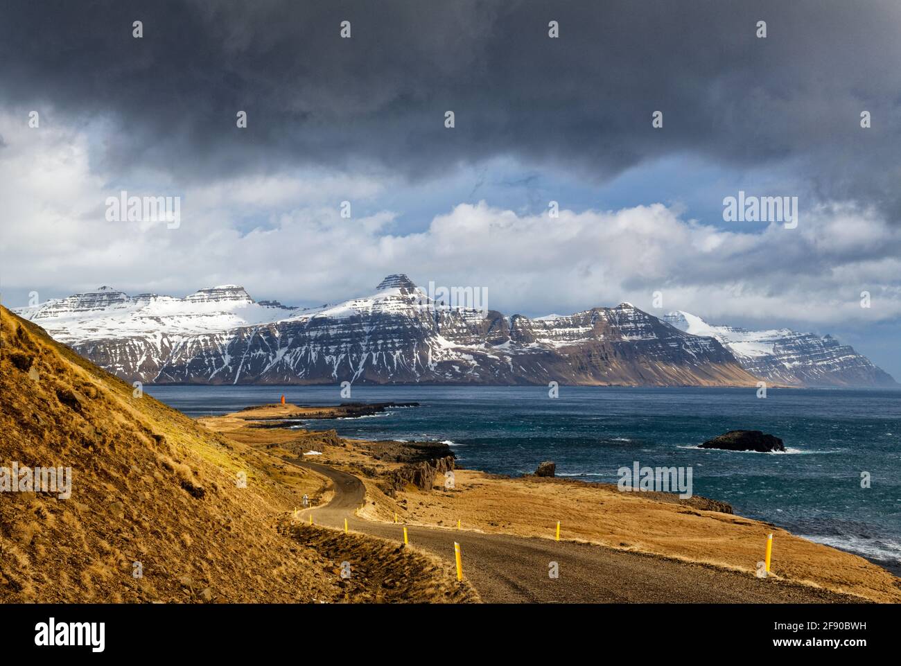 Landschaft mit Küstenstraße und schneebedeckten Bergen im Hintergrund, Island Stockfoto