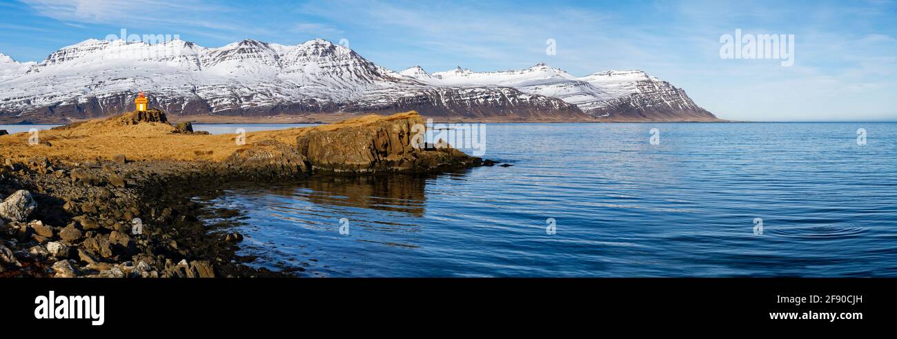 Landschaft mit Küste, Hügeln und fernem Leuchtturm, Djupivogur, Island Stockfoto