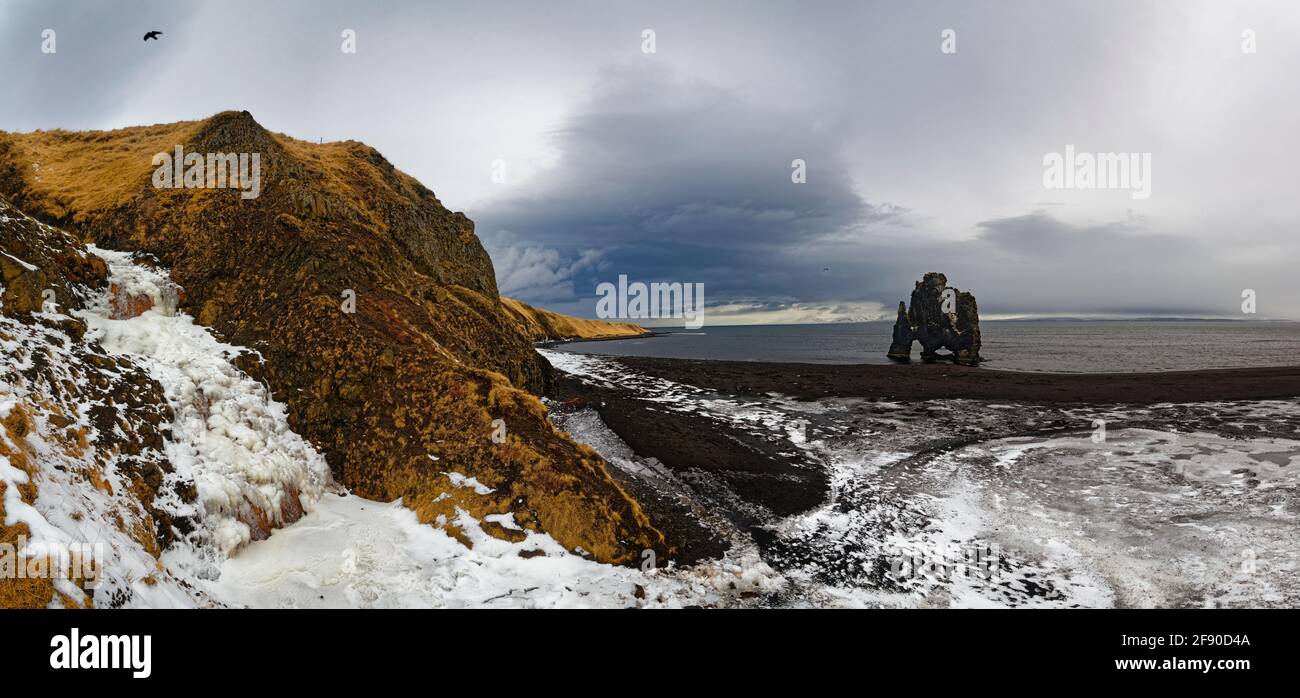 Karge Küstenlandschaft mit schneebedecktem Hügel, Island Stockfoto
