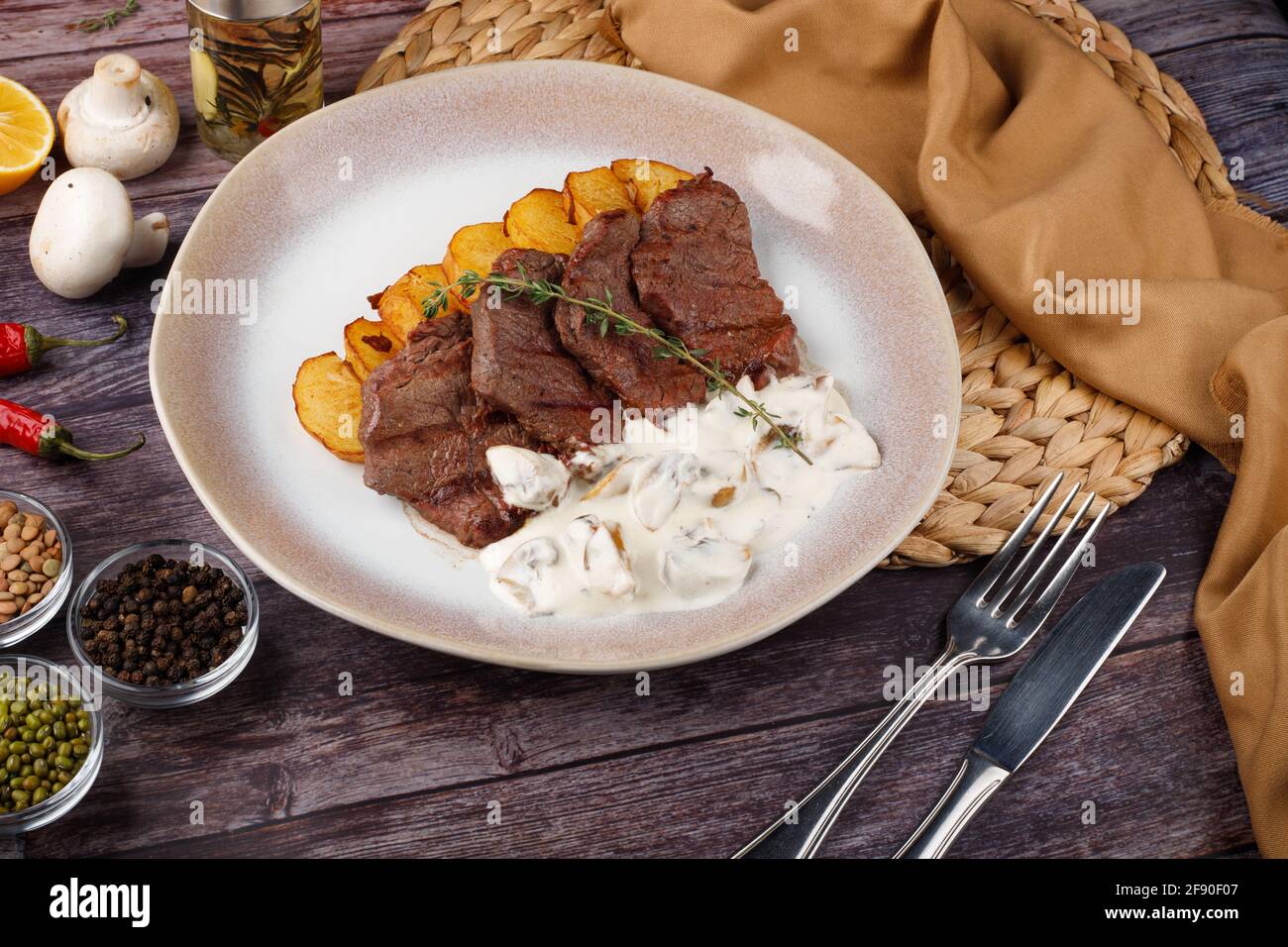 Dicke saftige Portionen gegrilltes Rinderfilet mit Pilzsauce Serviert mit Thymian-Kartoffeln auf einem alten Holztisch Stockfoto