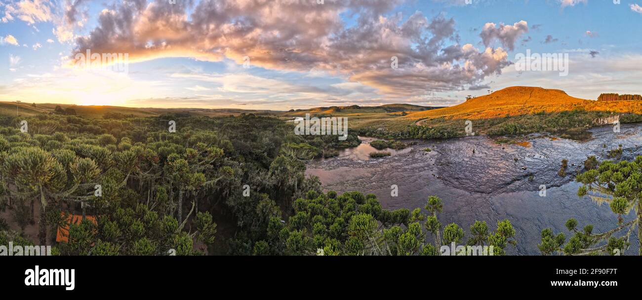 Panoramablick auf den Campingplatz in einem Araukaria-Wald vorbei Ein wunderschöner Fluss unter dem Sonnenuntergang Stockfoto