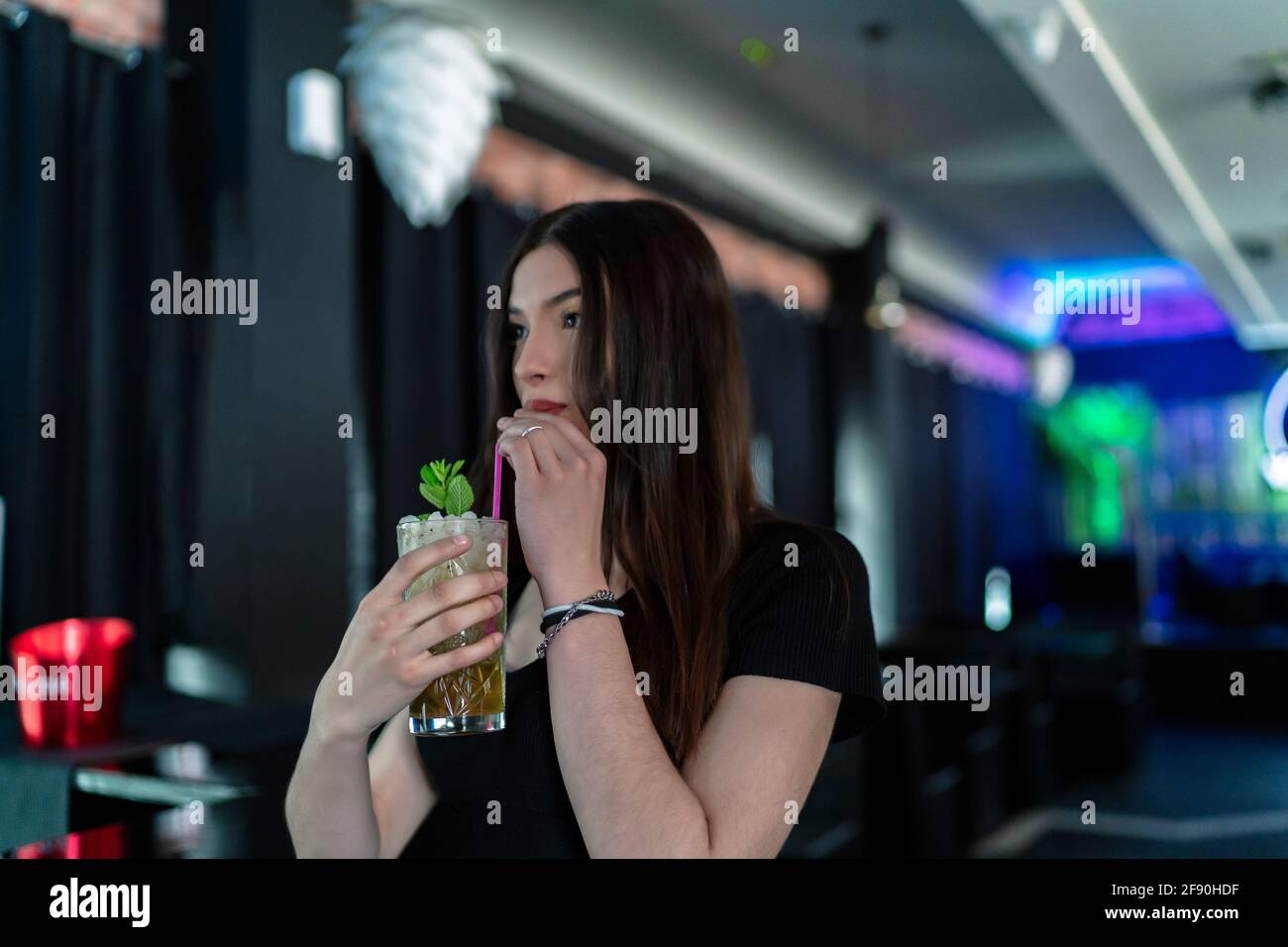 Schöne junge Frau, die in einem Pub einen Drink zu sich nehmen kann Stockfoto