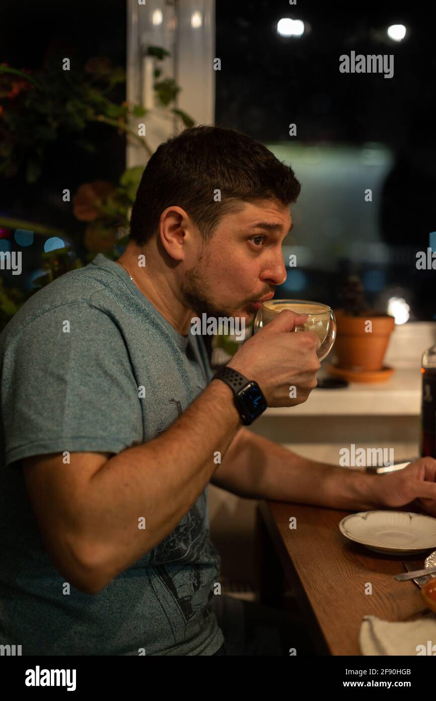 Ein Mann trinkt nachts Kaffee aus einem Glaskrug Stockfoto