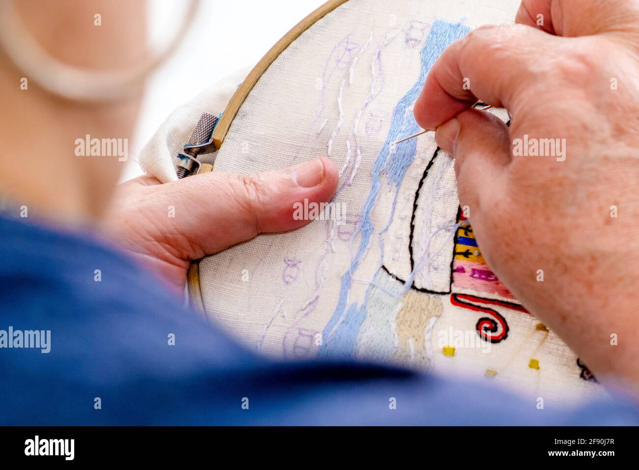 Nahaufnahme der Hände einer älteren Frau, die auf einem Stoff stickt. Tr Stockfoto