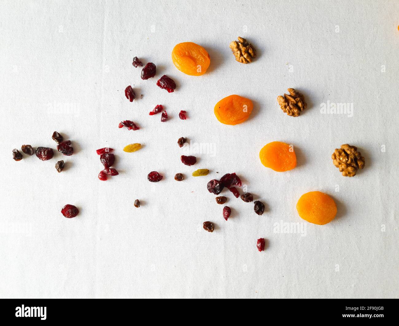 Walnüsse, Rosinen, getrocknete Preiselbeeren und getrocknete Aprikosen auf weißem Tisch Stockfoto