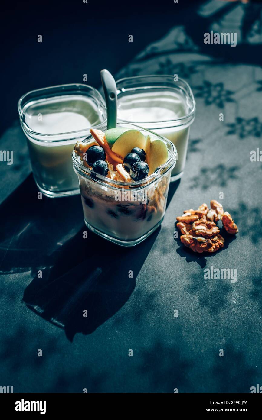 Joghurt mit Früchten im Glas auf schwarzem Tisch Stockfoto