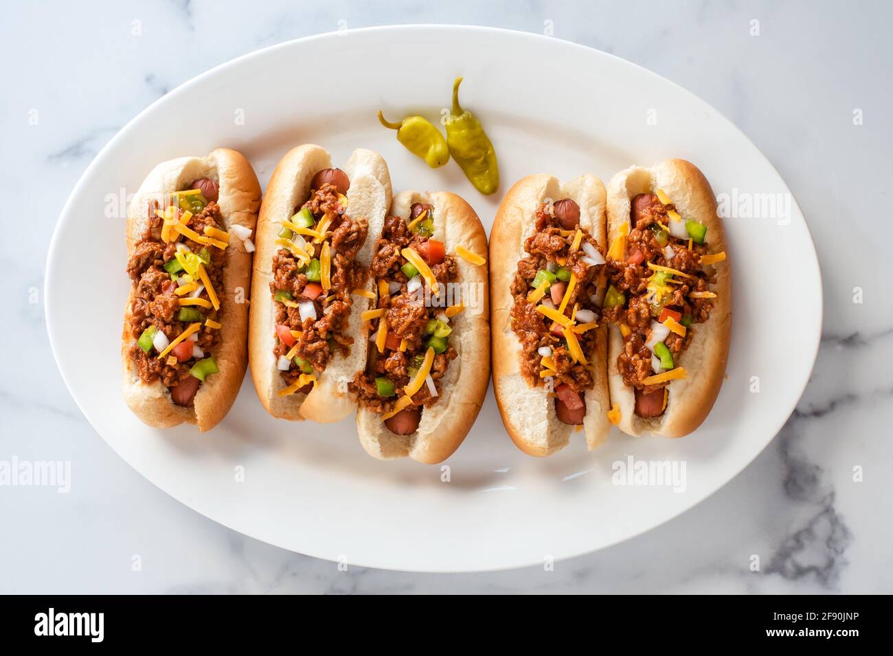 Ansicht von oben auf einem Teller mit Chilli-Hunden auf einer Theke aus weißem Marmor. Stockfoto