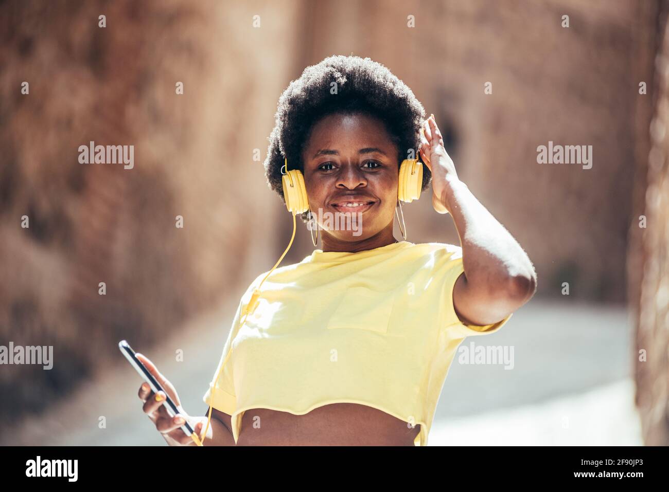 Porträt eines schwarzen Mädchens mit afro Haaren, das in einer alten Stadtstraße Musik hört und tanzt. Stockfoto