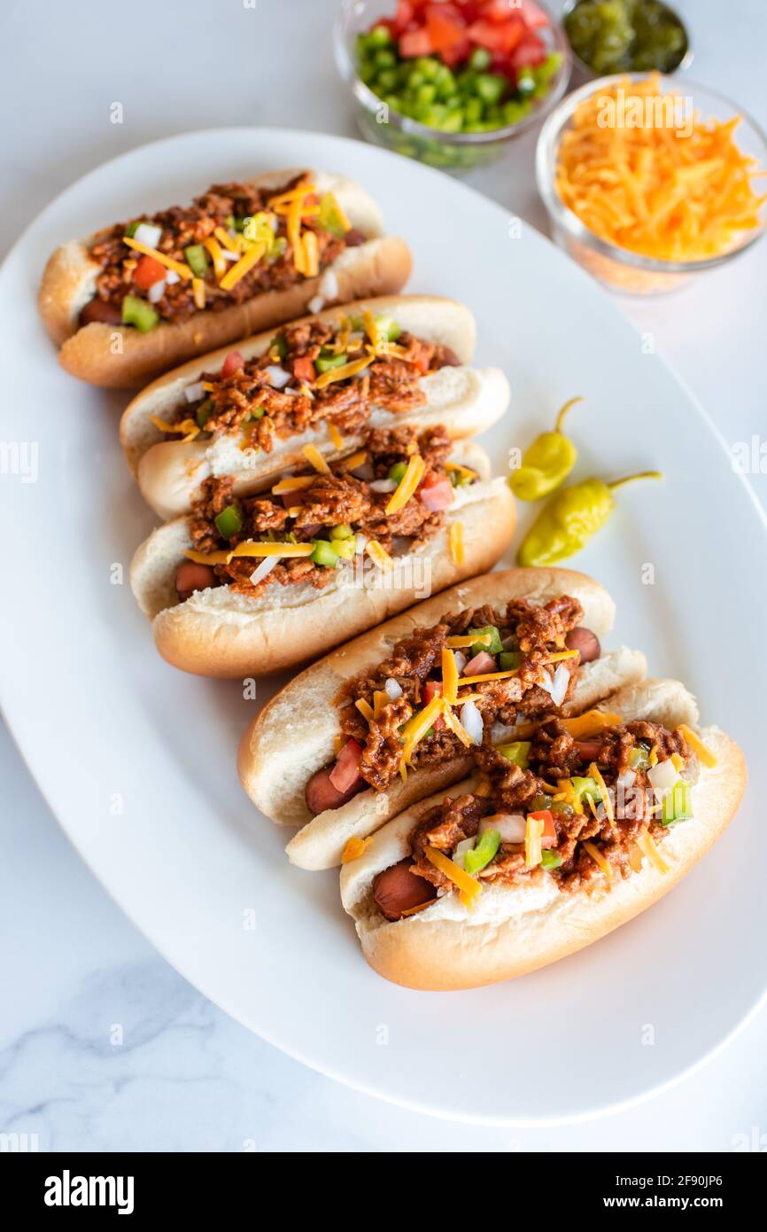 Nahaufnahme der Platte mit Chili-Hunden und Belag auf der Theke aus weißem Marmor. Stockfoto