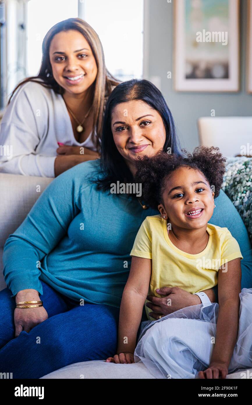 Portrait eines lächelnden Mädchens mit Mutter und Großmutter auf dem Sofa Zu Hause Stockfoto
