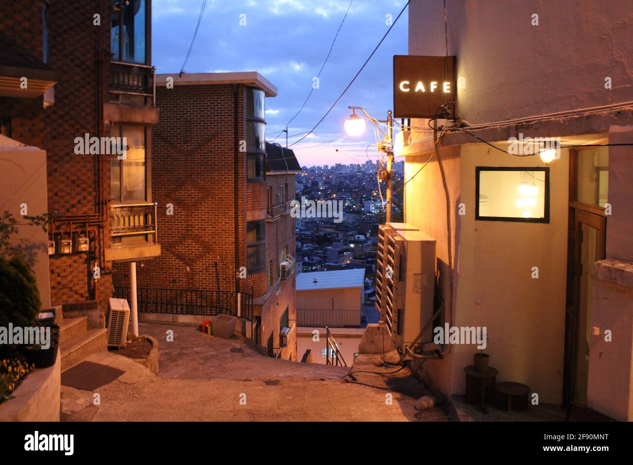 Blick in der Dämmerung auf den Eingang des Cafés mit der Skyline von Seoul im Hintergrund Stockfoto