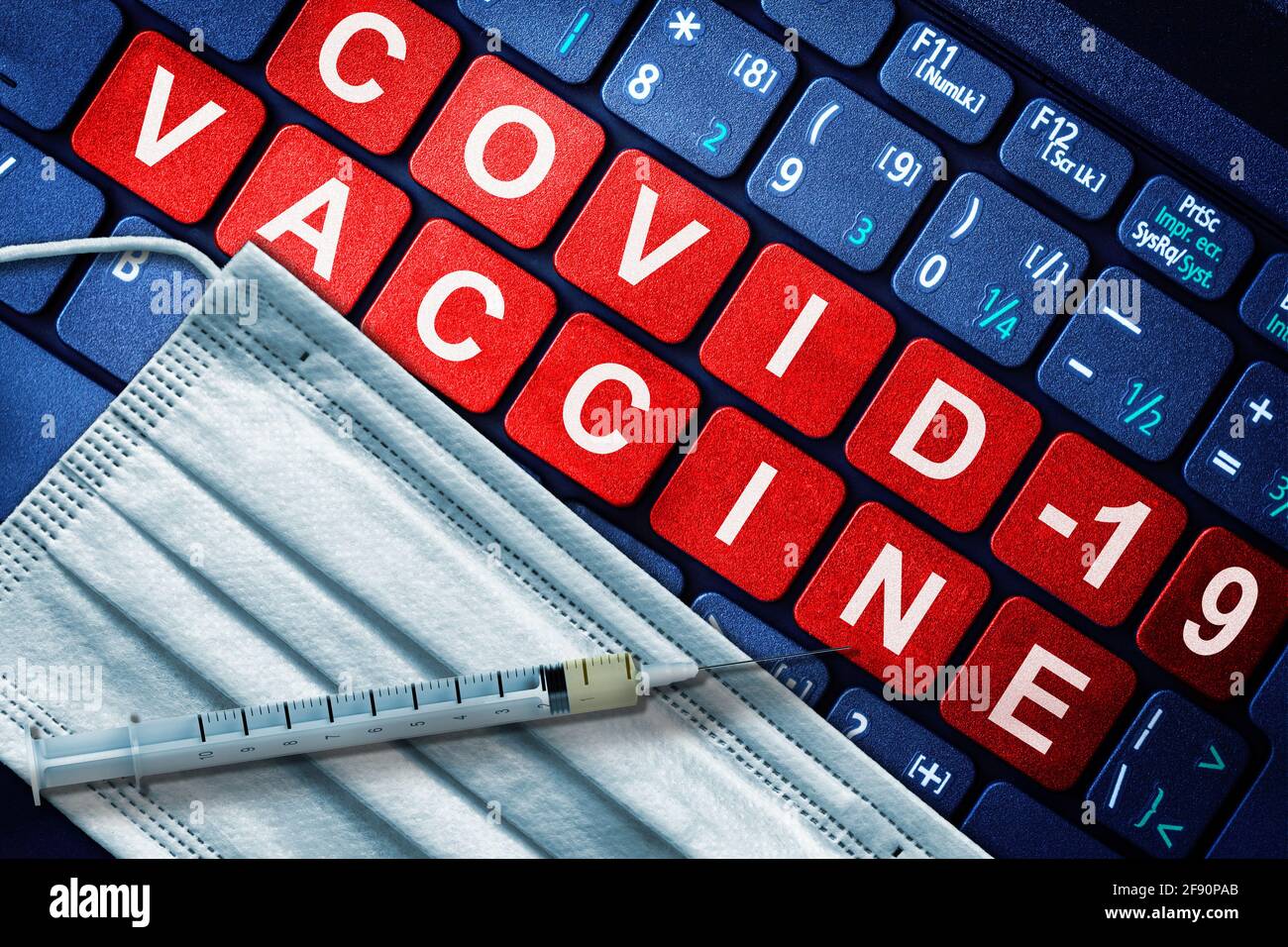 COVID-19-Immunisierung mit Spritze und Gesichtsmaske mit Impfmeldung auf der Computertastatur. Konzept der Online-Buchung für Impfstoffschoß Stockfoto