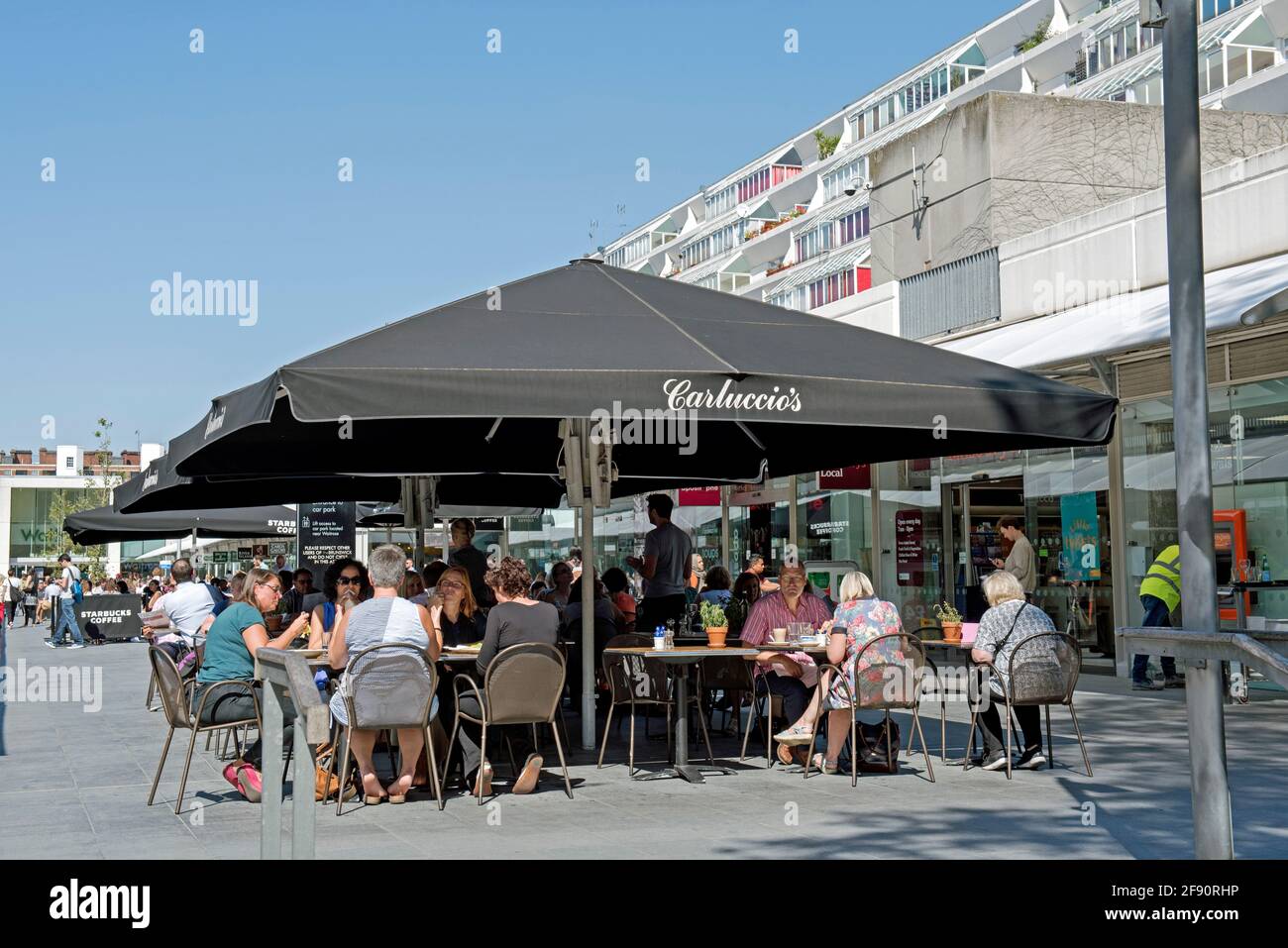 Carluccio's Café Leute sitzen und essen draußen unter der Baldachin oder zelten in strahlendem Sonnenschein, Brunswick Centre Bloomsbury London Borough of Camden UK Stockfoto