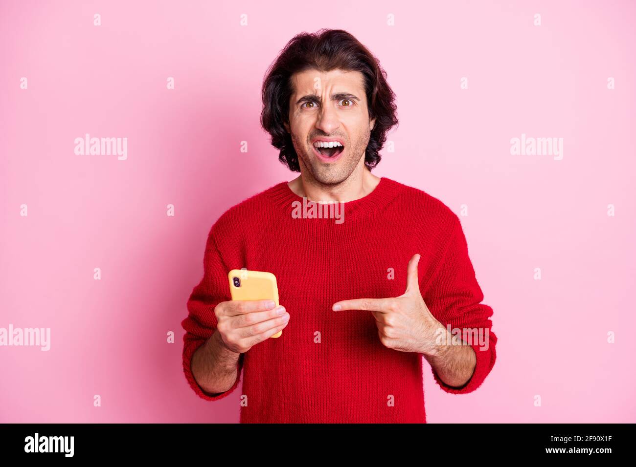 Porträt von verärgerten Brunet Kerl in den Händen halten Demonstratieren Gerät Fake News isoliert über rosa Hintergrund Stockfoto