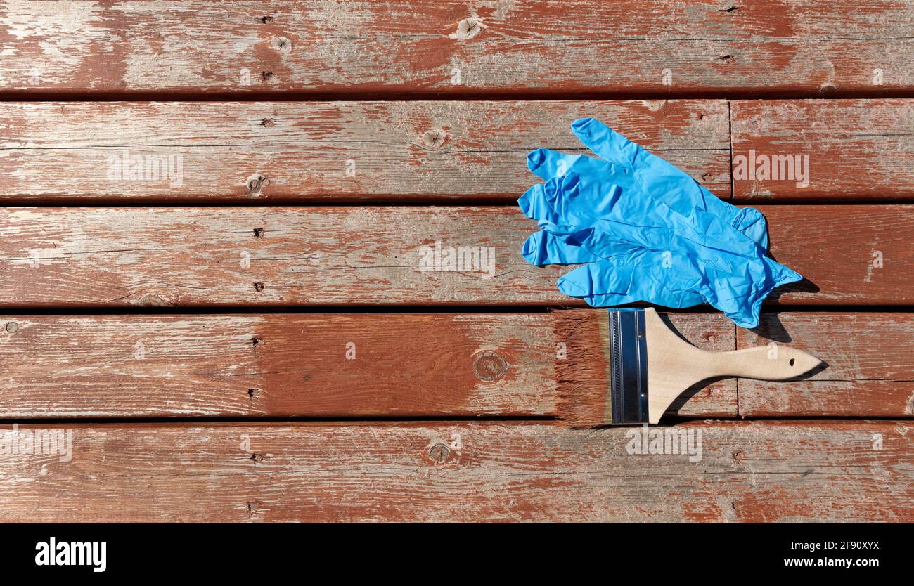 Pinsel mit Fleck auf Holz Zeder und Latex beladen Handschuhe zum Aufarbeiten des Wohndecks im flachen Lay-Format Stockfoto