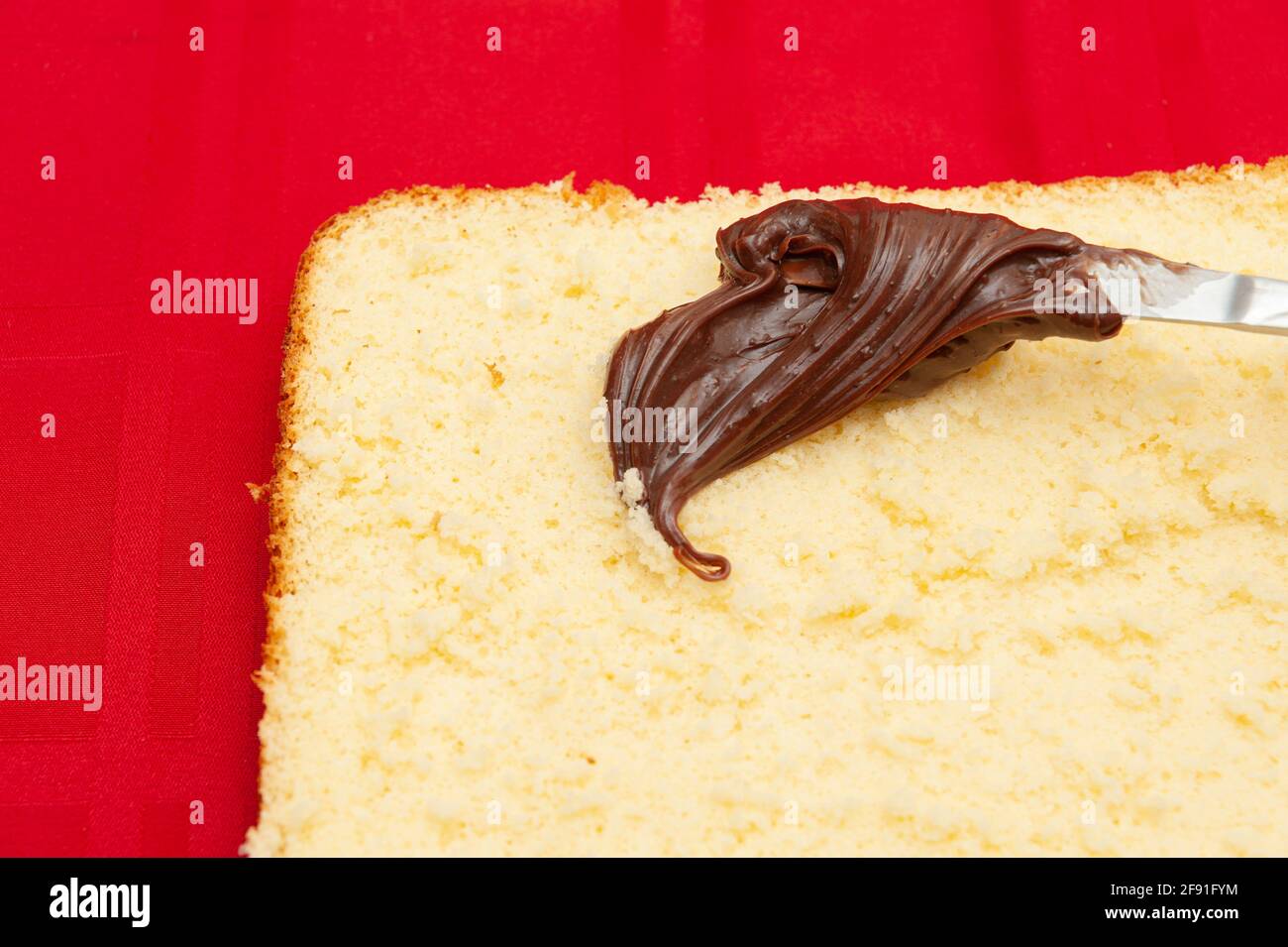 Stopfende hausgemachten Kuchen mit Schokolade Ganache. Isoliert auf rotem Hintergrund. Draufsicht. Stockfoto