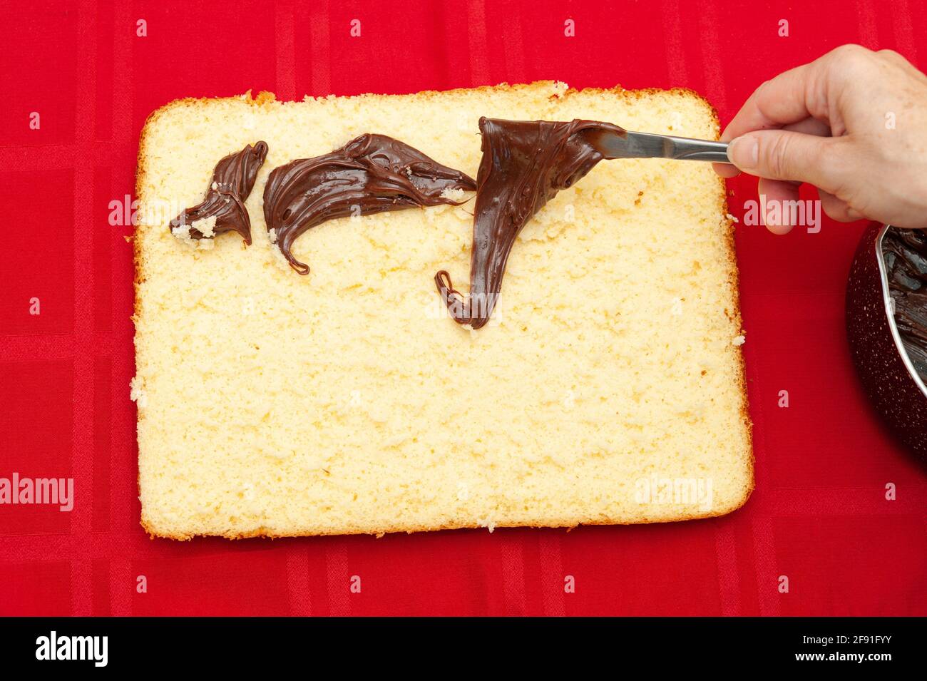 Handgefüllter hausgemachter Kuchen mit Schokoladenganache. Isoliert auf rotem Hintergrund. Draufsicht. Horizontale Aufnahme. Stockfoto