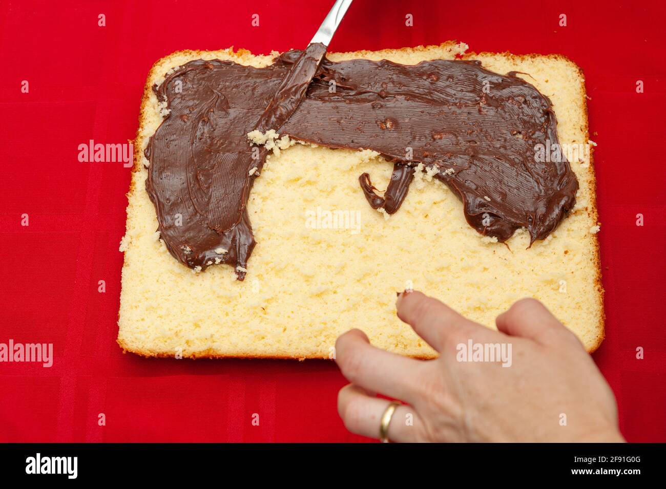 Handgefüllter hausgemachter Kuchen mit Schokoladenganache. Isoliert auf rotem Hintergrund. Draufsicht. Nahaufnahme. Stockfoto