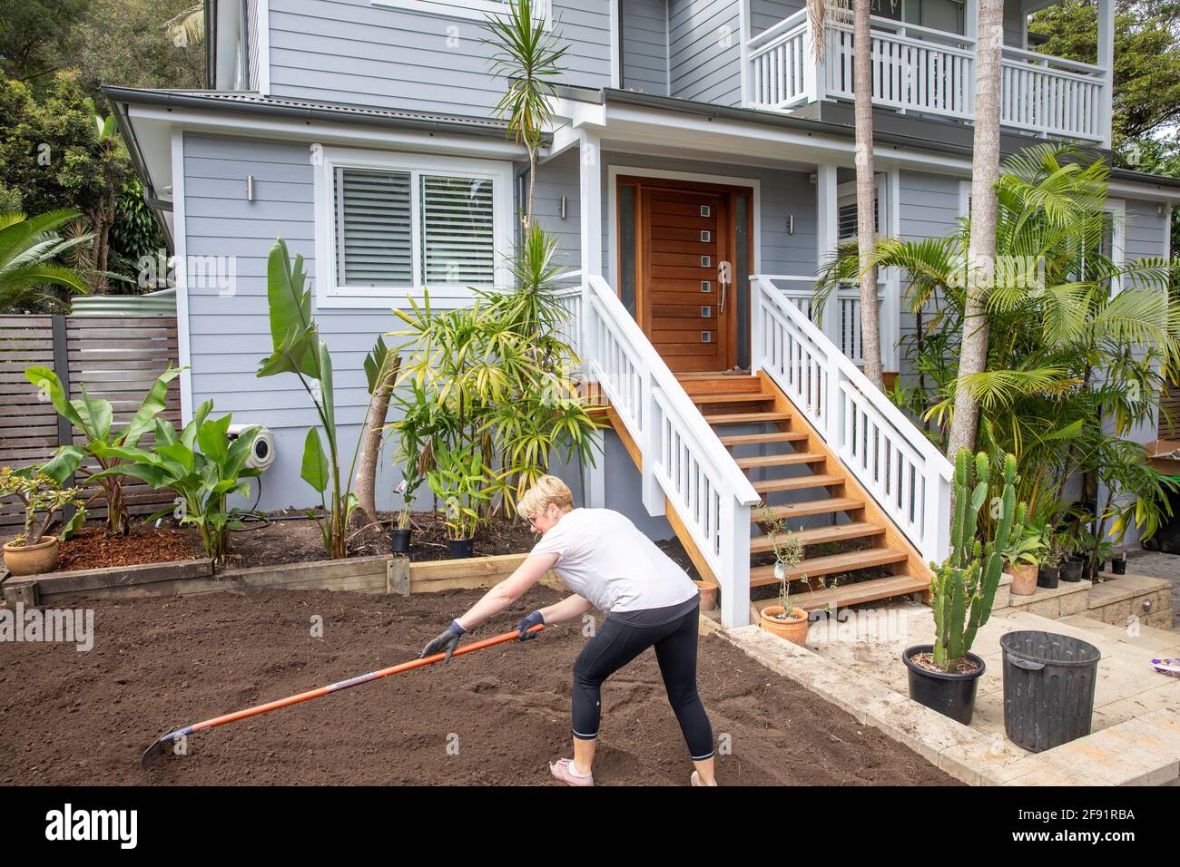 Australische Frau Modell freigegeben arbeiten auf dem Garten zu Hause Raking Boden, um für neue Rasen zu legen vorzubereiten, Sydney, NSW, Australien Stockfoto
