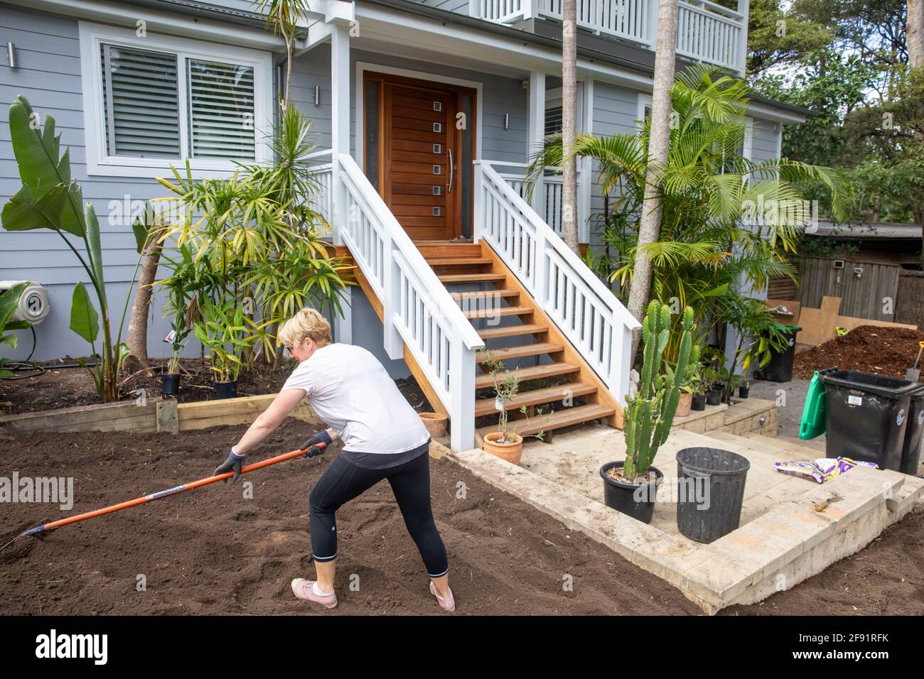 Australische Frau Modell freigegeben arbeiten auf dem Garten zu Hause Raking Boden, um für neue Rasen zu legen vorzubereiten, Sydney, NSW, Australien Stockfoto