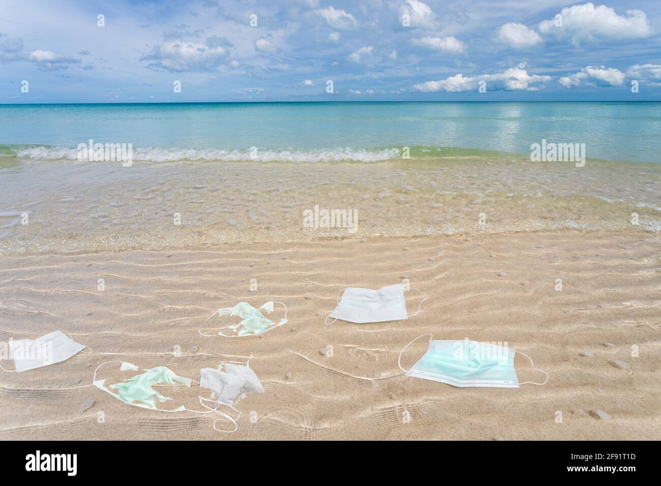 Müll aus gebrauchten medizinischen Masken am Strand. Stockfoto