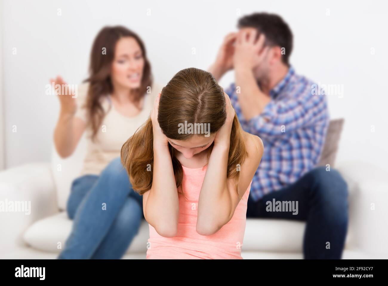 Eltern Sitzen Auf Dem Sofa Und Streiten Laut Hinter Dem Mädchen, Das Sie Bedeckt Ohren Stockfoto