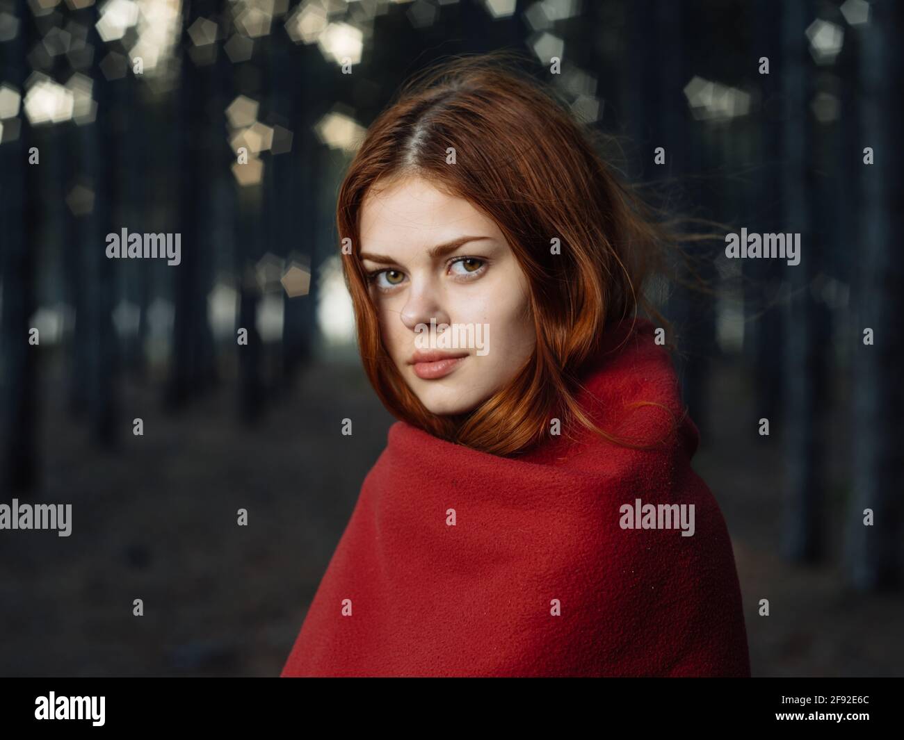 Eine Frau mit einem roten Karli auf ihren Schultern Die Bäume im Wald Stockfoto