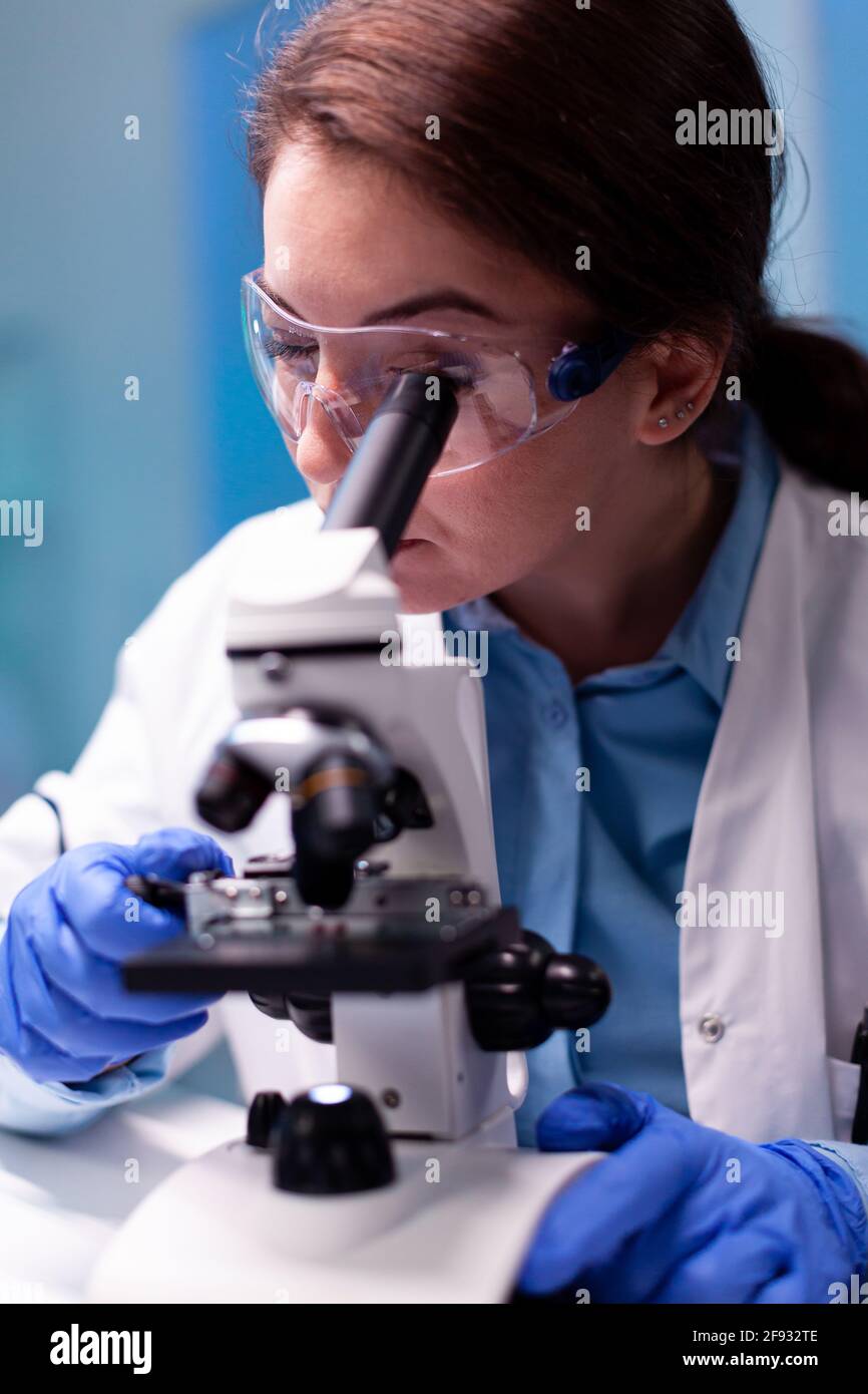 Medizinwissenschaftler analysiert einen Test mit Mikroskop für pharmazeutische Expertise. Modernes Labor mit Forschungsgeräten für Virusstudien und die Entwicklung von Impfstoffen. Stockfoto